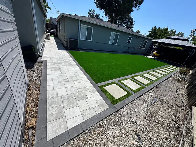 Paver walkway with a charcoal border beside turf and cast concrete stepping pads, built by CM Hardscape