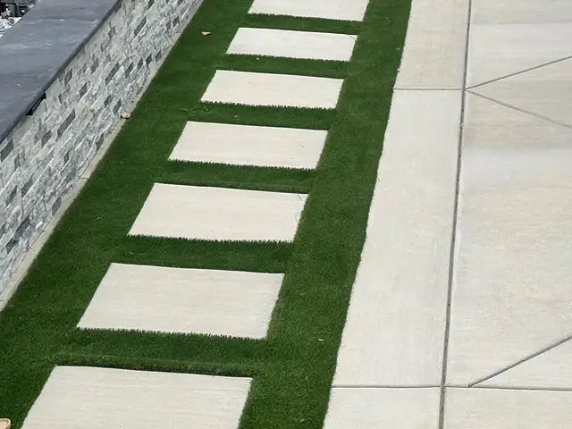 Broom-finished concrete patio with saw-cut joints and cast concrete stepping pads set in turf