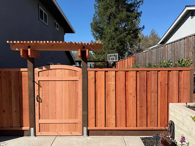 New redwood board-on-board fence with an arched gate and arbor, built by CM Hardscape