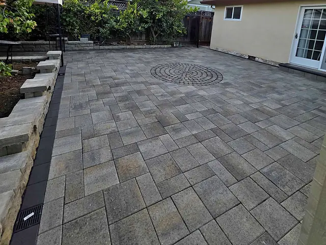 Grey paver patio with a circular cobblestone medallion, installed by CM Hardscape