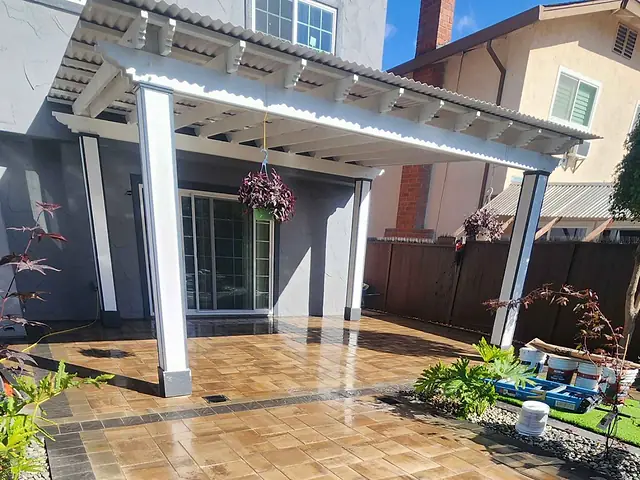 White lattice pergola over a paver patio at the back of a house