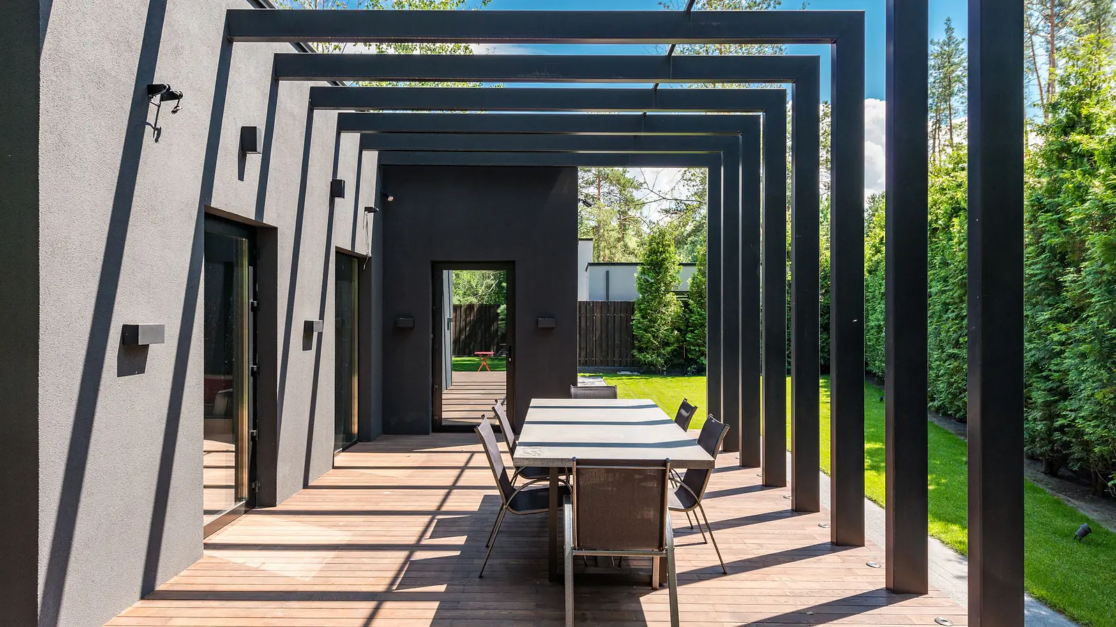 Modern pergola over an outdoor dining deck beside a house